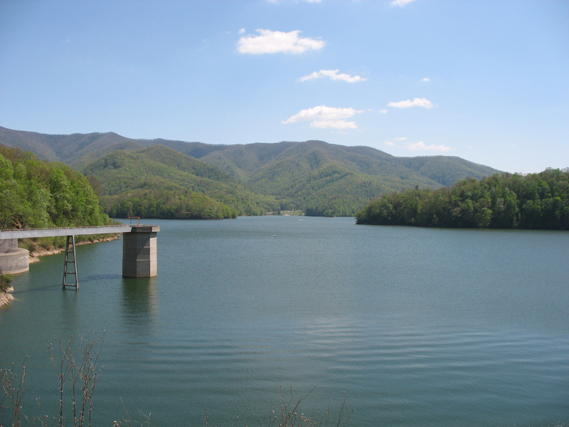 Watauga Lake bordered by green forested mountains beneath a blue sky